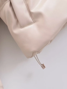 Dettaglio della giacca con cappuccio in ecopelle beige con cuciture e fermi per coulisse