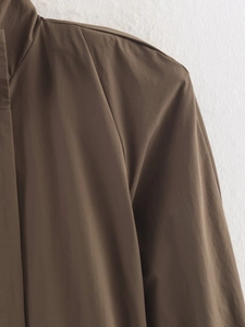 Détail de la couture de l'épaule et de la texture du tissu d'un trench marron ceinturé