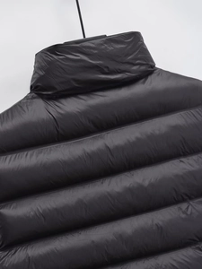 Détail de la texture matelassée et du col montant d'un gilet rembourré noir