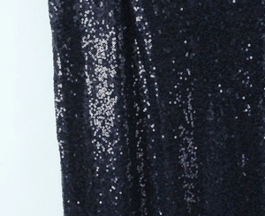 Detailed close-up of dark sparkling sequin fabric with dense reflective round sequins