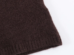 Detailed macro view of soft dark coffee knit fabric with ribbed hem and fuzzy texture