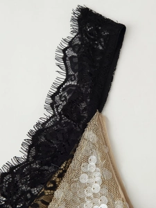 Detailed macro view of eyelash lace trim and silver sequins on champagne gold mesh fabric
