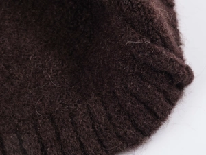 Detailed close-up of dark brown mohair knit fabric with ribbed edges on a sweater