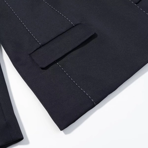 Detailed view of dark quilted blazer featuring decorative white running stitch on pocket
