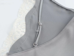 Dettaglio della spallina regolabile sul top in raso grigio con bordo in pizzo bianco