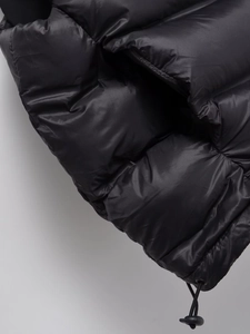 Détail de la veste matelassée noire brillante montrant le cordon de serrage au bas