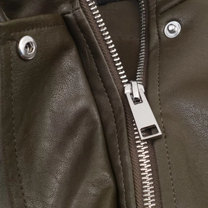 Macro shot of silver metal zipper and snap buttons on dark green leather flight jacket