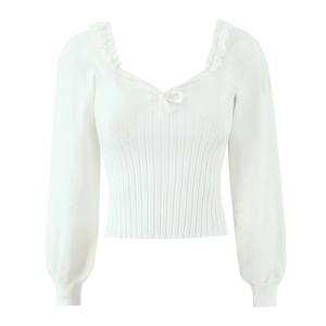 Détail d'un pull en maille blanc avec encolure en V à volants et petit nœud délicat