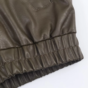 Detailed close-up of premium leather grain and ribbed elastic hem on bomber jacket