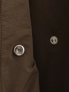 Détail macro des boutons-pression en métal sur le tissu tissé marron foncé du trench