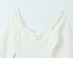 Détail du haut en maille blanche à col en V avec bordures à volants et nœud