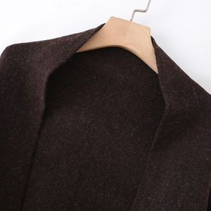Detailed close-up of dark brown knit scarf fabric showing rich textured wool fibers