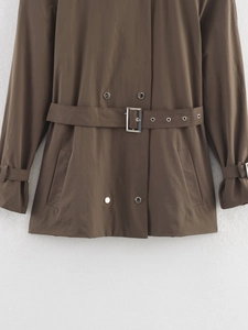 Détail d'un trench-coat marron foncé avec boutons croisés et une ceinture à la taille