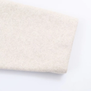 Nahaufnahme von beigem Wollstoff mit weichen Naturfasern und feinen Verarbeitungsdetails
