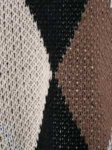 Close-up of diamond pattern knit fabric in black, brown and beige colors with soft texture