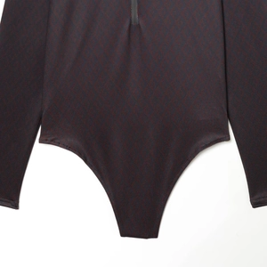 Détail du body à manches longues avec motif géométrique rouge foncé et fermeture éclair