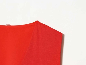 Vue détaillée de la robe rouge à col en V montrant le tissu texturé et les coutures fines