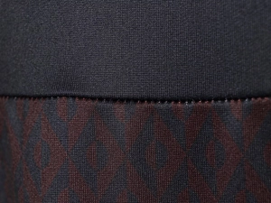 Détail macro du tricot côtelé noir et du tissu à motifs géométriques rouge foncé