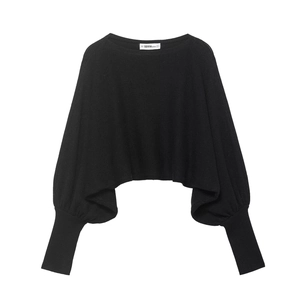 Détail du pull en tricot noir montrant les poignets côtelés et l'étiquette de cou