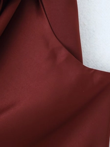 Macro detail of wine red asymmetric dress showing silky fabric texture and drape