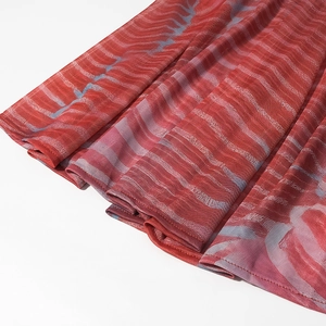 Detailed view of the red abstract print pleated skirt fabric texture and mesh material