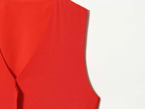 Gros plan d'une robe rouge sans manches avec col en V montrant la texture du tissu et couture