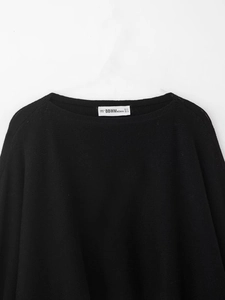 Gros plan sur l'encolure ronde et la texture du tissu d'un pull noir en maille fine