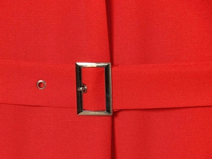 Détail de robe rouge sans manches avec ceinture à boucle rectangulaire en métal argenté