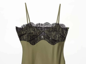 Close-up of olive green satin dress with intricate black eyelash lace trim and silk texture