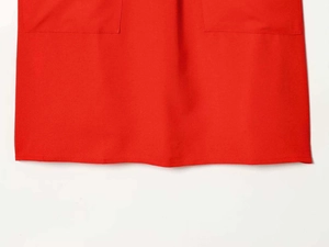 Détail de la robe rouge sans manches montrant deux poches carrées et des coutures fines