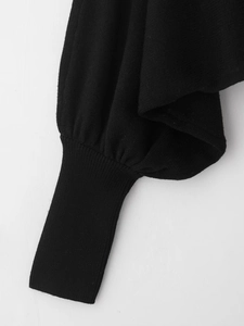 Détail d'un pull noir en maille avec poignets côtelés et manches bouffantes plissées