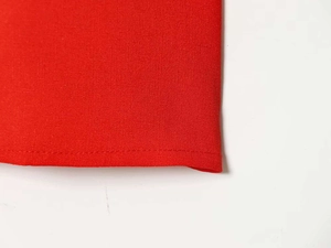 Gros plan sur la texture du tissu rouge avec ourlet à couture simple bien alignée