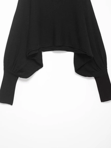 Détail d'un pull noir avec manches bouffantes et longs poignets en maille côtelée