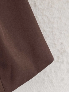 Detail of dark brown satin fabric texture on blazer showing premium smooth finish
