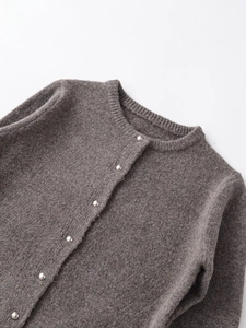 Dettaglio cardigan in maglia grigia con scollo rotondo e bottoni in metallo argento