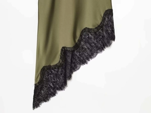 Close-up of olive green satin dress featuring delicate black eyelash lace trim at the hem