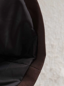 Close-up of brown twill fabric with black satin lining showing premium stitching details