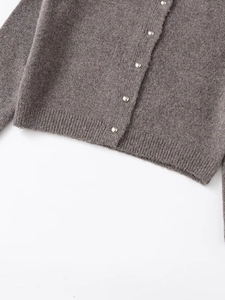 Dettaglio del cardigan in maglia tortora con bottoni metallici e orlo a costine