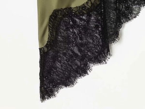 Detailed close-up of olive green satin fabric with delicate black eyelash lace trim detail