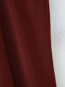 Vue détaillée de la texture du tissu satiné rouge foncé sur l'élégante robe midi