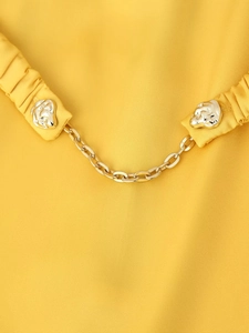 Detail of yellow dress fabric with silver abstract buttons and fine gold metal chain link