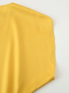 Close-up of seamless shoulder stitching on yellow satin midi dress with fine fabric texture