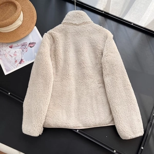 Detail view of the back of a cream-colored fleece jacket with stand-up collar and warm texture