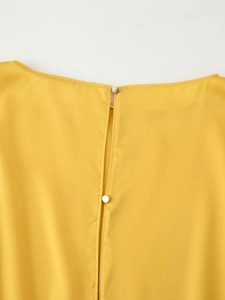 Detail of yellow satin dress back with vertical slit and two elegant gold buttons