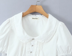 Détail du chemisier blanc à manches bouffantes avec col Claudine en dentelle fine