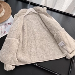 Detail of beige fleece jacket showing soft curly texture and full front zipper closure
