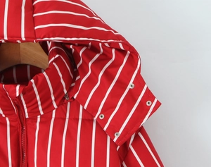 Close-up of winter hooded jacket featuring red and white vertical stripes and metal snaps