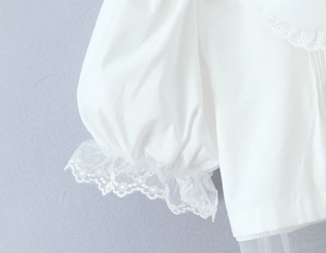Détail de manchette bouffante blanche avec dentelle florale et bord brodé festonné