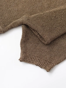 Detailed close-up of metallic knit sweater fabric with ribbing and hollow-out texture