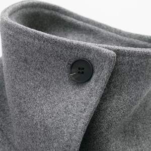 Detail of grey wool coat collar showing compact fabric texture and black button